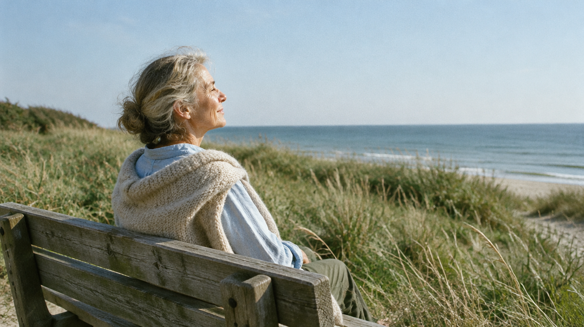 Frau sitzt in der Herbstsonne auf einer Bank an der Ostsee
